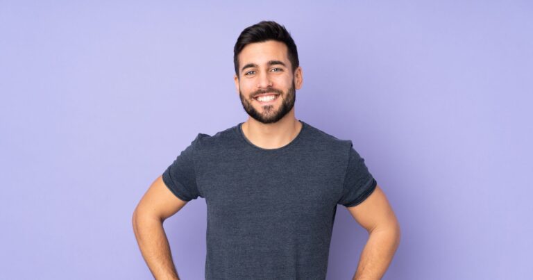 Caucasian handsome man posing with arms at hip and smiling
